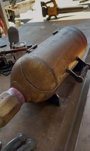 Homemade welding rig truck grill fabricated from a recycled steel cylinder with welded legs, hinged lid, and spring handle