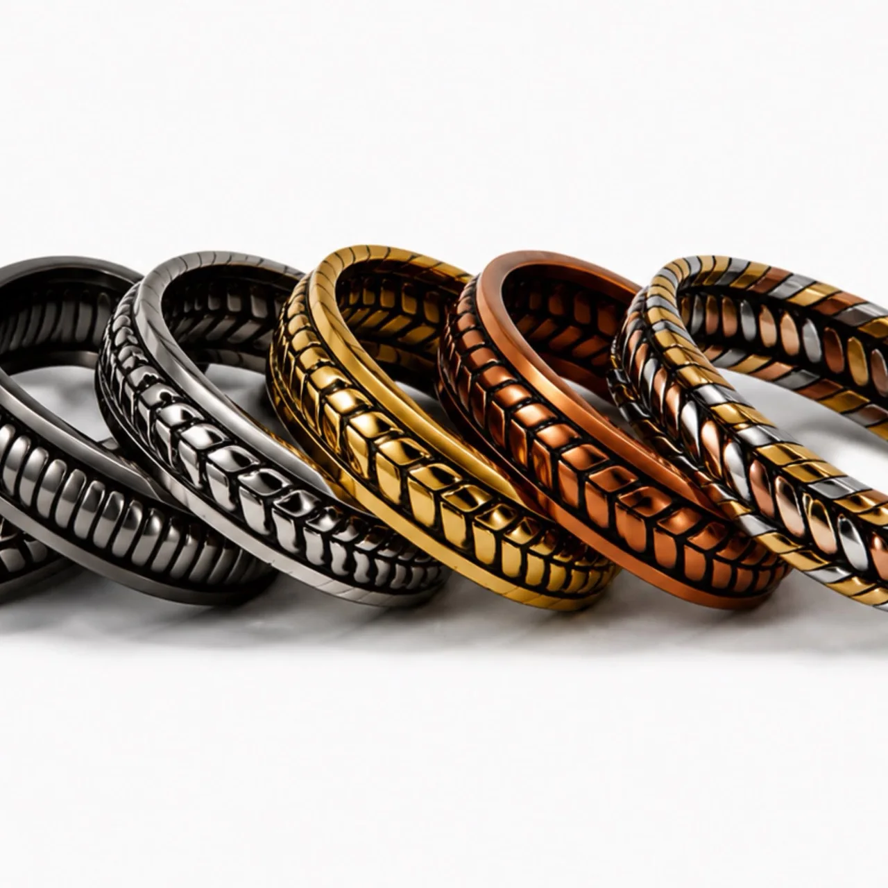 Six engraved metal cuff bracelets stacked together in silver, black, gold, copper, and multicolor finishes.