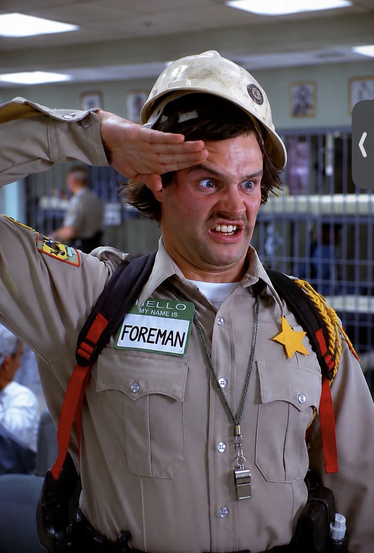 Uniformed foreman wearing a campaign hat and pointing to his head in a humorous jobsite image.